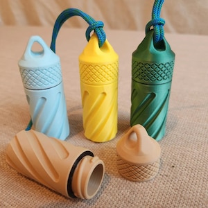 Puede incluir: Una colección de coloridos recipientes cilíndricos con superficies texturizadas y cordones adjuntos. Los recipientes son de color azul, amarillo y verde, con un recipiente y tapa de color beige en primer plano. El diseño presenta un patrón en espiral.