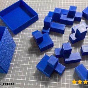 May include: A selection of bright blue 3D-printed geometric shapes, including cubes and rectangular prisms, arranged on a grey grid surface. Two open blue boxes are also present. The image includes the text "@vaclavh_797838" and a five-star rating.