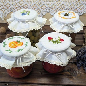 Handgeborduurde linnen potdeksels: fruit- en honingmotieven, kanten rand