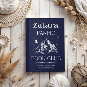 May include: A blue book with white text that reads "Zutara FANFIC BOOK CLUB" and a quote that reads "You rise with the moon, I rise with the sun". The book cover features a white mountain range with a dragon flying above it.