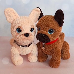 Pode incluir: Dois brinquedos de pelúcia feitos à mão de buldogues franceses. Um é rosa claro com uma coleira com tachas, o outro é marrom com uma coleira vermelha. Ambos têm olhos azuis e narizes pretos.