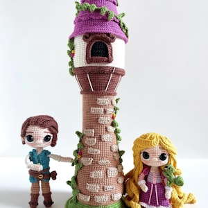 May include: A crochet set featuring a tall, cylindrical tower with a purple roof and stone-patterned walls, accompanied by two small dolls. One doll has short brown hair and a blue vest, while the other has long yellow hair and a purple dress.