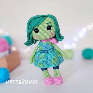 Könnte beinhalten: Gehäkelte Puppe, die einer Figur aus dem Film Alles steht Kopf ähnelt. Die Puppe hat grüne Haut und Haare, ein türkisfarbenes Kleid mit gestickten Details und rosa Schuhe. Der Text "PATTERN PDF" ist unten sichtbar.