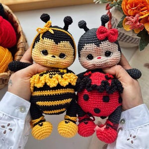 May include: Two handmade crochet dolls: a yellow and black bee and a red and black ladybug. The bee has a yellow bow and the ladybug has a red bow. Both have black eyes and antennae. The dolls are soft and plush.