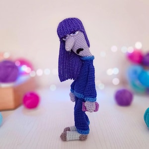 Può includere: Bambola all'uncinetto fatta a mano che raffigura il personaggio Tristezza del film Inside Out. La bambola presenta un cappello viola lavorato a maglia, lunghi capelli blu e un completo blu. Il viso della bambola è grigio con un'espressione triste.