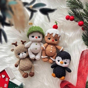 Könnte beinhalten: Eine Sammlung handgefertigter Weihnachtsornamente aus Häkelarbeit. Das Set beinhaltet ein Rentier, einen Schneemann, einen Lebkuchenmann und einen Pinguin. Jedes Ornament ist mit detaillierten Nähten und leuchtenden Farben gefertigt.