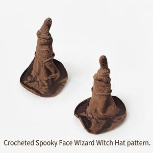 May include: Two brown crocheted wizard or witch hats with a textured, slumped appearance and a wide brim. The hats feature a pointed, folded top section and a dark brown base. The text below reads: Crocheted Spooky Face Wizard Witch Hat pattern.