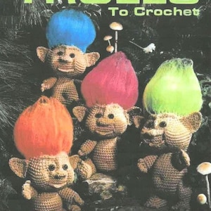 May include: Image of a book cover titled "TROLLS To Crochet". The cover features several crocheted troll dolls with colorful hair in blue, pink, orange, and green. The dolls have smiling faces and are set against a dark background.