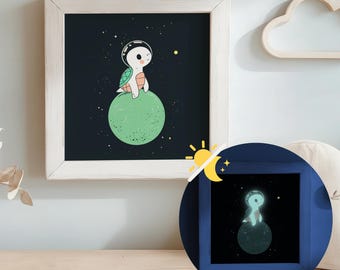 Puede incluir: Una ilustración enmarcada de una tortuga de dibujos animados con un casco espacial sentada en un planeta verde en el espacio. El fondo es negro con estrellas blancas. El marco es blanco con un acabado de madera clara.
