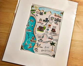 May include: A hand-drawn map of Los Angeles, California, featuring colourful illustrations of landmarks and neighbourhoods. The map includes Hollywood, Westwood, Santa Monica, Venice, and Downtown Los Angeles.