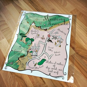 May include: A hand-drawn map of the Monterey Peninsula in California, featuring landmarks like Pacific Grove, Carmel-by-the-Sea, and Carmel Valley Ranch. The map is illustrated with whimsical details, including a lighthouse, a whale, and a glass of wine.