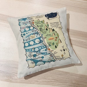 May include: A decorative map-style pillow featuring a stylized illustration of Big Sur, California. The pillow is white with a blue and green map design. The map includes landmarks like Point Sur Lighthouse, Limekin State Park, and the Big Sur River. The text "Visit Beautiful Big Sur California" is featured on the map.