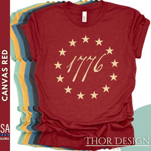 May include: Red t-shirt with a circle of stars and the text "1776" in a cream colour.