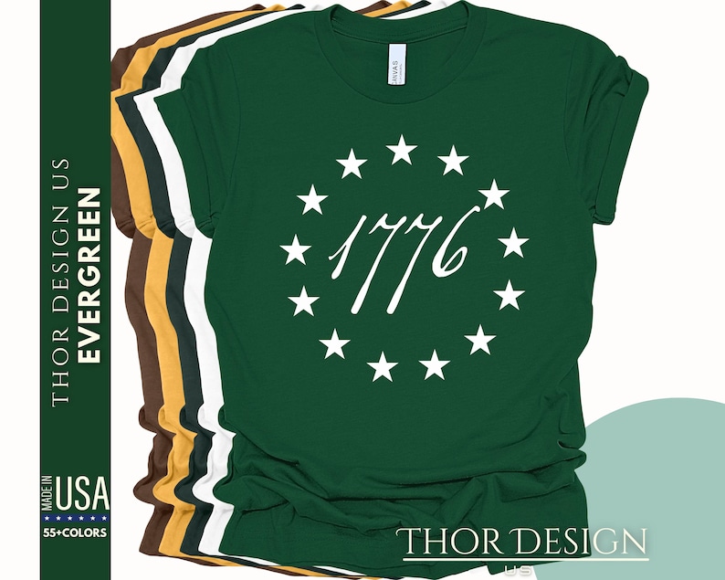 Pode incluir: Uma camiseta verde com um c&iacute;rculo branco de estrelas e o texto "1776" em uma fonte cursiva.
