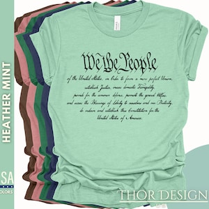 May include: A green t-shirt with the text "We the People" in black lettering. The text is a quote from the US Constitution. The shirt is available in a variety of colors.