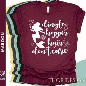 May include: A maroon t-shirt with a white graphic of a mermaid with the text "dingle hopper hair don't care".