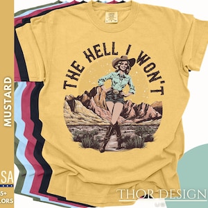 May include: A yellow t-shirt featuring a vintage-style graphic of a woman in a cowboy hat and the text "THE HELL I WON'T".