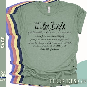 May include: Sage green t-shirt with the text "We the People" and the preamble to the United States Constitution printed in black.