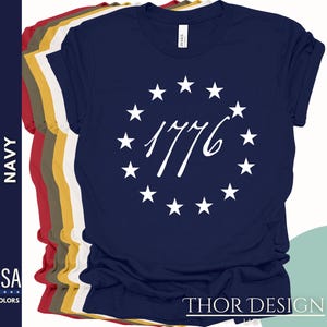 Pode incluir: Camiseta azul marinho com um c&iacute;rculo branco de estrelas e o texto "1776" em uma fonte cursiva.