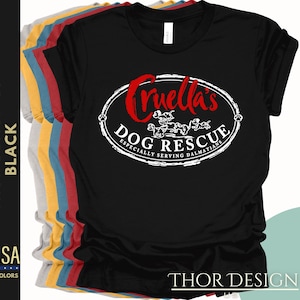 May include: Black t-shirt with the text "Cruella's Dog Rescue" in a white oval design. The text "Especially Serving Dalmatians" is below the logo. The word "Cruella's" is in red. The shirt is from Thor Design US.