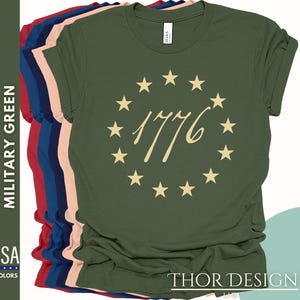 May include: A green t-shirt featuring a circle of stars and the text "1776" in gold. The shirt is available in a range of colours.