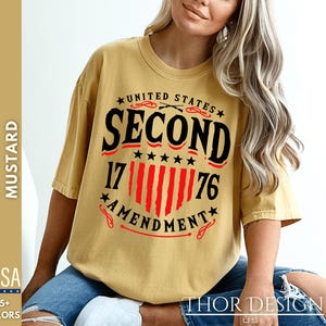 May include: A mustard yellow t-shirt with a black and red graphic design that says "United States Second Amendment 17|||||||76".