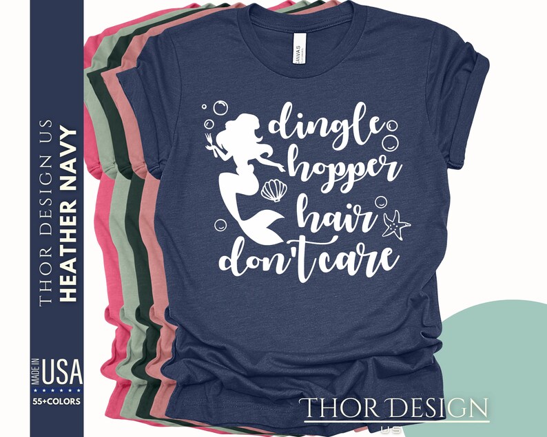 May include: A navy blue t-shirt with a white graphic of a mermaid with the text "dingle hopper hair don't care".
