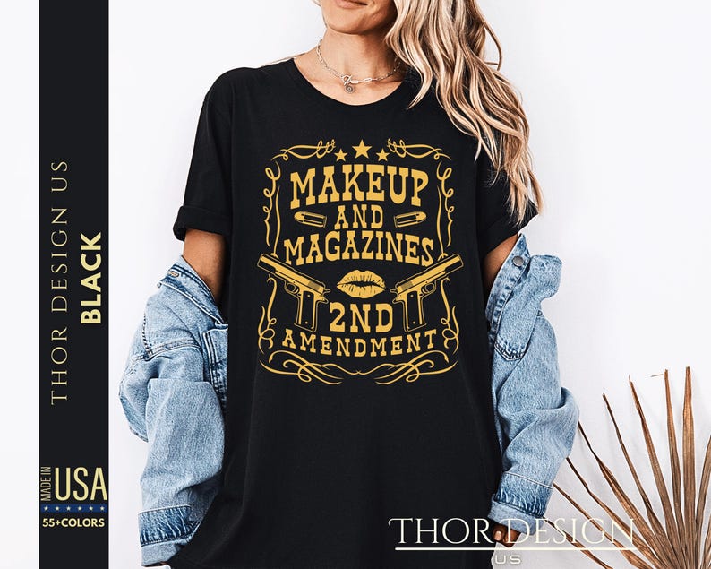 May include: Black t-shirt with a gold graphic design that says "Makeup and Magazines 2nd Amendment". The graphic features two pistols and a lipstick kiss.