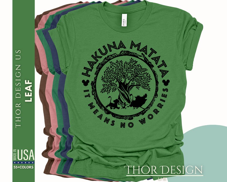 Puede incluir: Camiseta verde con un gr&aacute;fico circular negro que presenta un &aacute;rbol, animales y el texto "Hakuna Matata It Means No Worries".