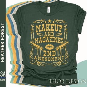 May include: A green t-shirt with a yellow graphic design that says "Makeup and Magazines 2nd Amendment". The graphic features two guns and a lipstick kiss.