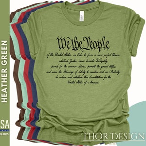 May include: A green t-shirt featuring the text "We the People" and the preamble to the United States Constitution printed in black. The shirt is available in a range of colours.