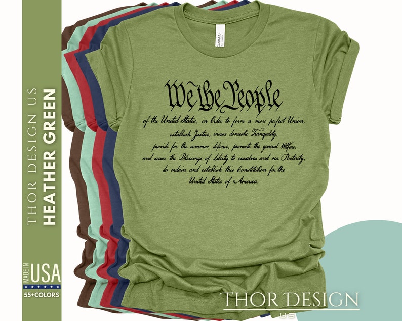 May include: A green t-shirt with the text "We the People" and the preamble to the United States Constitution printed in black. The shirt is available in a variety of colors.