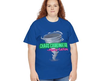 May include: A blue t-shirt with the words "CHAOS COORDINATOR -Mama Edition" in green and pink, featuring a graphic of a tornado. The shirt is made of a soft material and is suitable for casual wear.