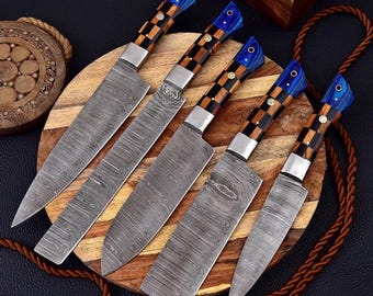 May include: Five Damascus steel chef knives with patterned blades and handles. The handles feature a checkered design with blue and brown accents. The knives are arranged on a wooden cutting board, showcasing their craftsmanship and design.