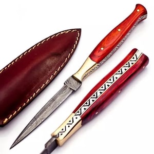 May include: A red and gold-colored knife with a patterned handle and a leather sheath. The blade is made of Damascus steel.