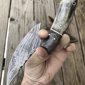 May include: A handmade knife with a Damascus steel blade and a bone handle. The handle has a brass accent and a dark brown leather sheath.