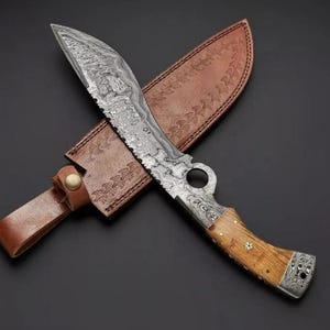 Op de afbeelding: Een Damascus staal mes met een bruine leren schede. Het mes heeft een houten handvat en een decoratief patroon op het lemmet.