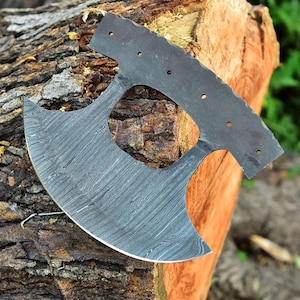 May include: A large, curved, black and silver axe with a unique, patterned blade. The axe is made of metal and has a hole in the center of the blade.