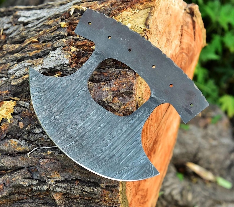 May include: A large, curved, black and silver axe with a unique, patterned blade. The axe is made of metal and has a hole in the center of the blade.