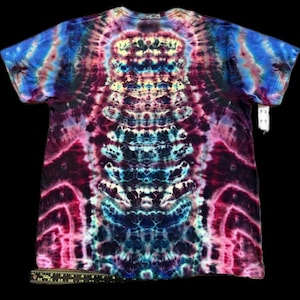 May include: A tie-dye t-shirt with a symmetrical pattern in shades of blue, purple, pink, and yellow. The short-sleeved shirt has an intricate design, with the tie-dye effect creating a unique and artistic appearance. The shirt's design is detailed and eye-catching.