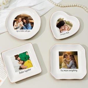 May include: Four white ceramic trinket dishes with gold rims. Each dish features a photograph and a handwritten message: "Life is better with you," "Love you Mom," "Better together," and "You mean everything."