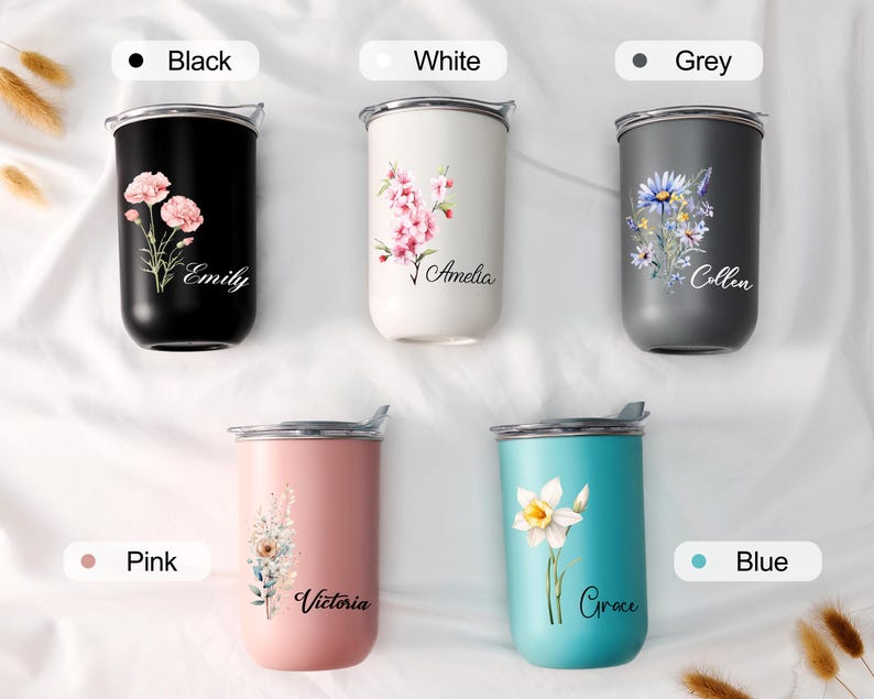 Op de afbeelding: Vijf ge&iuml;soleerde bekers in zwart, wit, grijs, roze en blauw. Elke beker heeft een bloemenontwerp en een naam. De zwarte beker heeft roze bloemen en de naam "Emily". De witte beker heeft roze bloemen en de naam "Amelia". De grijze beker heeft blauwe en gele bloemen en de naam "Collen". De roze beker heeft een bloemenontwerp en de naam "Victoria". De blauwe beker heeft een witte bloem en de naam "Grace".