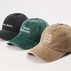 Può includere: Tre cappellini da baseball neri, verdi e beige. Ogni cappellino ha un testo ricamato bianco: "Team Sherbs", "Custom Embroidery" e "Social Swim Squad". I cappellini sono realizzati in un tessuto morbido e usurato.