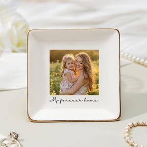 May include: A square, white ceramic trinket dish with a gold rim. The center features a color photograph of a woman and child. The words "My forever home" are written in script below the photo.