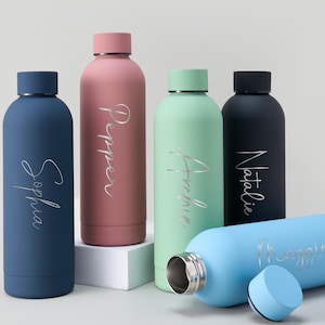 May include: A collection of personalized water bottles in various colors, including blue, pink, green, and black. Each bottle features a name in a silver script font. One bottle is lying on its side with the cap removed.