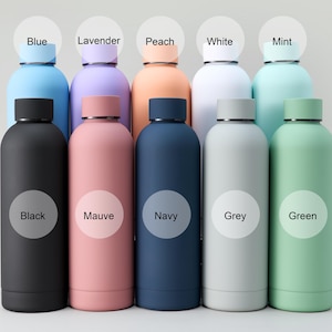 May include: A collection of insulated water bottles in various colors, including black, mauve, navy, grey, and green. Each bottle has a matching lid and a label indicating its color, such as "Blue," "Lavender," and "Peach."
