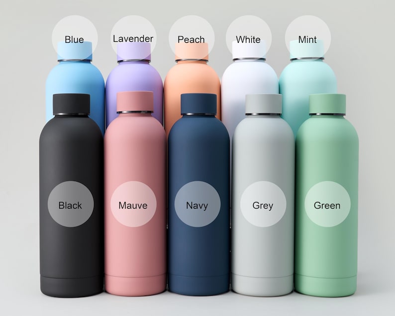 May include: A collection of insulated water bottles in various colors, including black, mauve, navy, grey, and green. Each bottle has a matching lid and a label indicating its color, such as "Blue," "Lavender," and "Peach."