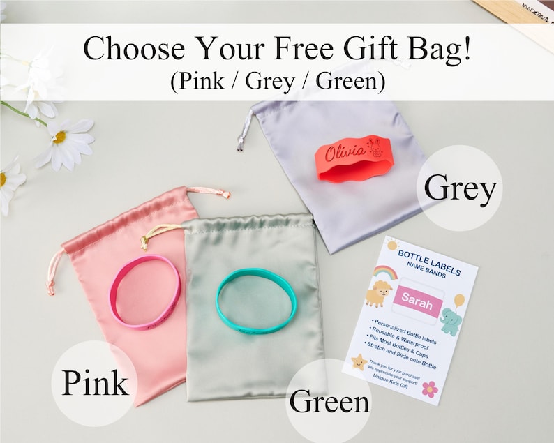 May include: Three satin drawstring gift bags in pink, grey, and green, each paired with a silicone bottle band. The grey bag features an orange band with the name Olivia. A white informational card displays the text Bottle Labels Name Bands.