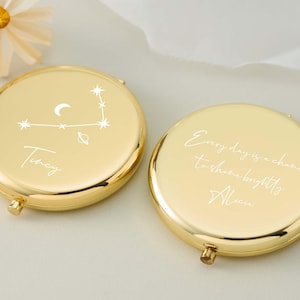May include: Two gold-coloured, round compact mirrors. One mirror features a constellation design with the name "Tracy". The other mirror has the inscription "Every day is a chance to shine brightly, Alison."