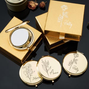 May include: Gold compact mirrors with floral engravings and personalized names, presented in matching gold gift boxes. The compacts feature a round shape and a hinged opening, perfect for a cosmetic accessory.